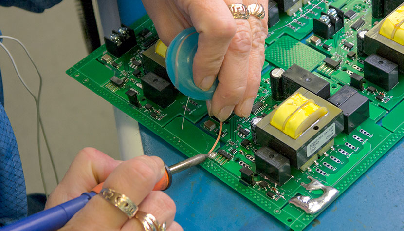 A worker soldering a circuit board